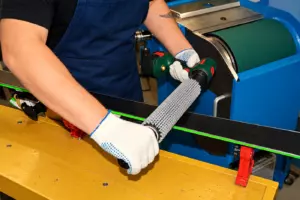 Мастер обрабатывает скользящую поверхность лыжи роторной щёткой