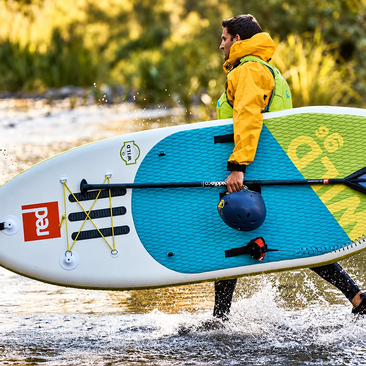Райдер переносит доску Red Paddle Wild, весло и шлем.